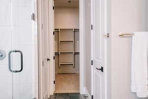 Full bath with a stall shower, dark tile patterned floors, a spacious closet, and dark carpet