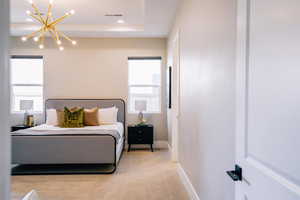 Bedroom featuring light colored carpet, a chandelier, a tray ceiling, and recessed lighting