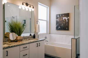 Bathroom featuring plenty of natural light, double vanity, a bath, and a shower with shower door