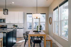 Kitchen with decorative backsplash, light wood-type flooring, white cabinets, appliances with stainless steel finishes, and recessed lighting