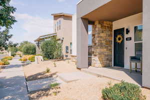 Entrance to property with stone siding, stucco siding, and a porch