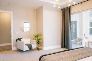 Carpeted bedroom featuring baseboards and a chandelier