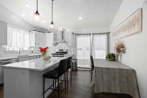 Kitchen featuring tasteful backsplash, decorative light fixtures, appliances with stainless steel finishes, a kitchen breakfast bar, and white cabinetry