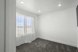 Empty room with dark colored carpet and recessed lighting