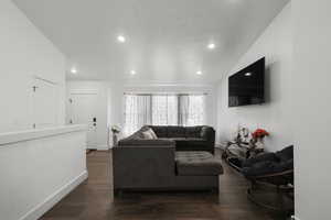 Living area featuring dark wood-style floors, lofted ceiling, and recessed lighting