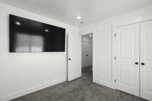 Unfurnished bedroom featuring dark colored carpet and a closet