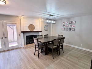 Dining area with a glass covered fireplace, light wood-style floors, and a textured ceiling