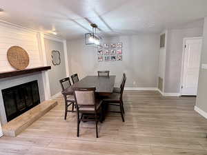Dining space with a large fireplace and light wood-style flooring