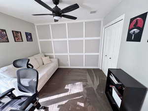 Home office featuring a ceiling fan and dark colored carpet
