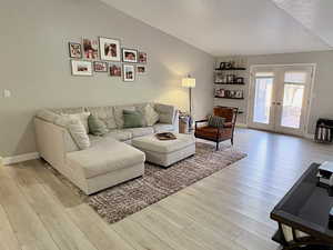 Living area featuring vaulted ceiling, light wood-type flooring, and french doors