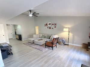 Living room with light wood-type flooring, ceiling fan, and high vaulted ceiling