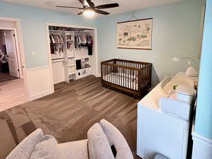 Carpeted bedroom with a nursery area, a closet, and ceiling fan