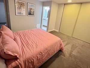 Carpeted bedroom featuring connected bathroom and a closet