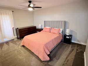 Carpeted bedroom featuring ceiling fan and baseboards