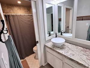 Full bath with a shower with shower curtain, vanity, and light tile patterned floors