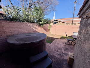 Fenced backyard featuring a patio, outdoor dining area, and a hot tub