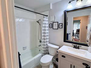 Full bathroom with shower / bath combo with shower curtain, vanity, and a textured wall