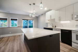 Kitchen featuring dark cabinetry, light wood-style floors, white appliances, and white cabinets