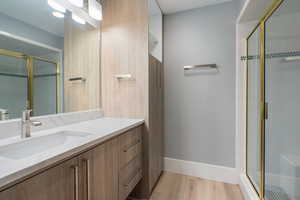 Full bath with vanity, a shower stall, and light wood-type flooring