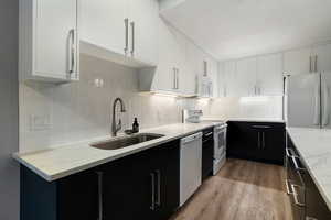 Kitchen featuring dark cabinets, white appliances, and white cabinetry