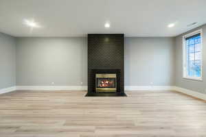 Unfurnished living room featuring a tile fireplace, light wood-style flooring, and recessed lighting