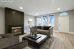 Living room with a tile fireplace, wood finished floors, and recessed lighting