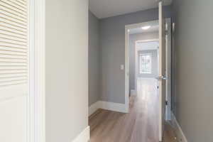 Corridor with light wood-style flooring and baseboards