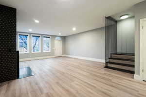 Unfurnished living room with recessed lighting, light wood finished floors, and stairway
