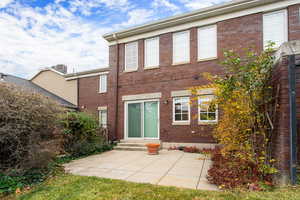 Rear view of property featuring entry steps, a patio, and brick siding
