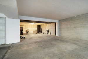 Unfinished below grade area with concrete block wall and a textured ceiling