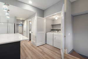 Washroom with light wood-style flooring and washer and clothes dryer