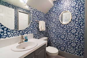 Half bath featuring vanity and wallpapered walls