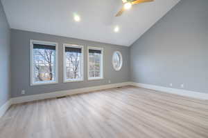 Spare room with light wood-style floors, high vaulted ceiling, and a ceiling fan