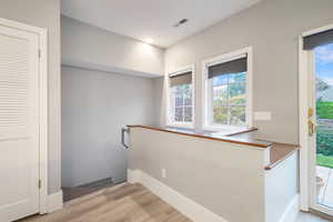Corridor featuring an upstairs landing, light wood-style flooring, and recessed lighting
