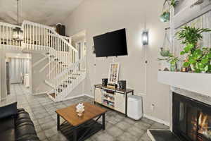 Living area featuring stairs, a high ceiling, and a glass covered fireplace