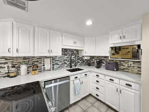 Kitchen with white cabinets, stainless steel appliances, light stone countertops, light tile patterned floors, and recessed lighting