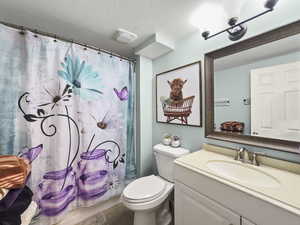 Full bath featuring vanity, a textured ceiling, and shower / bathtub combination with curtain