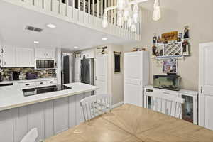Kitchen featuring white cabinetry, a kitchen bar, backsplash, recessed lighting, and a peninsula