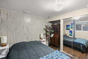 Bedroom with a closet, wood finished floors, and wood walls