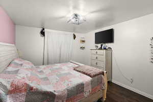Bedroom featuring dark wood-style flooring and baseboards