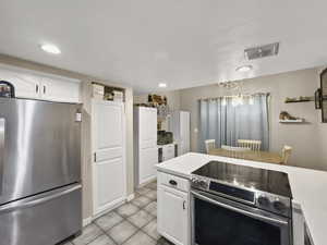 Kitchen with appliances with stainless steel finishes, white cabinetry, light countertops, and light tile patterned flooring