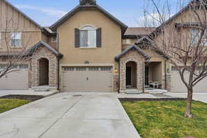 View of front of property featuring stone siding, stucco siding, a garage, and concrete driveway
