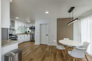Kitchen featuring appliances with stainless steel finishes, dark wood finished floors, white cabinetry, recessed lighting, and a textured ceiling