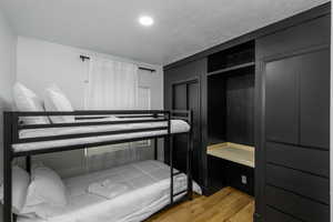 Bedroom featuring light wood-style floors, two closets, and a textured ceiling