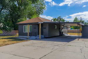 View of front of property with driveway, a carport, and a shingled roof