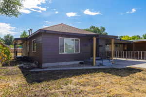 Rear view of property featuring a shingled roof and an attached carport