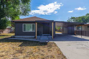 View of front of home featuring concrete driveway, an attached carport, and a shingled roof