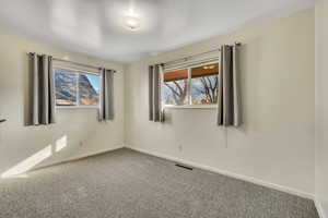 Carpeted spare room featuring baseboards
