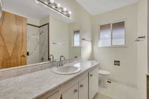 Full bathroom with vanity, a marble finish shower, and light tile patterned floors