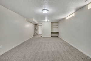 Finished below grade area featuring light colored carpet, a textured ceiling, and stairway